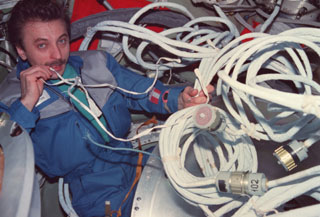 Lazutkin tries to organize cables in the center node of the Mir